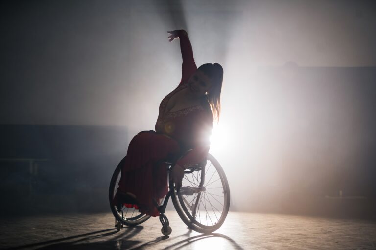 Asset id: 2508825717 Woman with a disability, a para dancer practicing choreography at the dance studio, making wheelchair spin and elegant arm moves.
